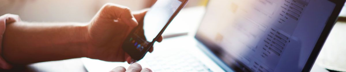 Man using mobile phone whilst looking at laptop